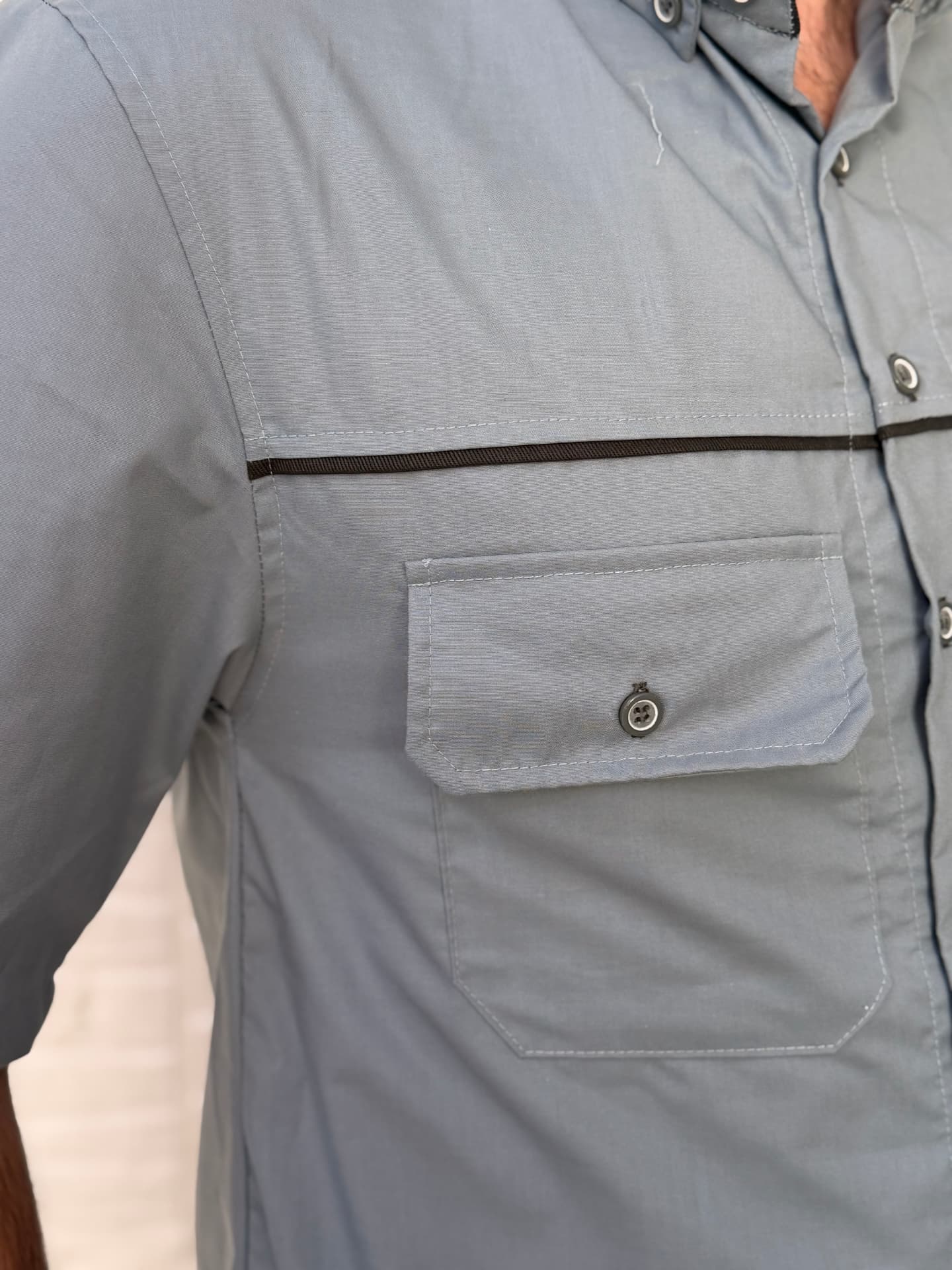 Detalhe do bolso, do vivo preto e das costuras da camisa operacional cinza