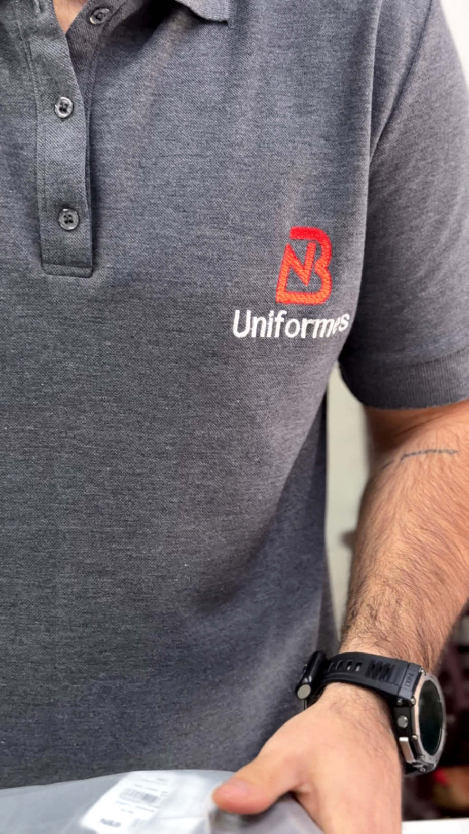 Colaborador vestindo polo cinza com bordado NB Uniformes