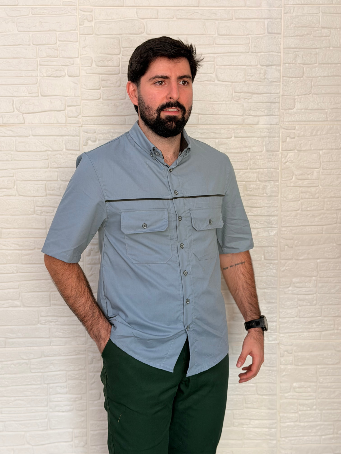 Colaborador com camisa operacional cinza de manga curta e calça verde